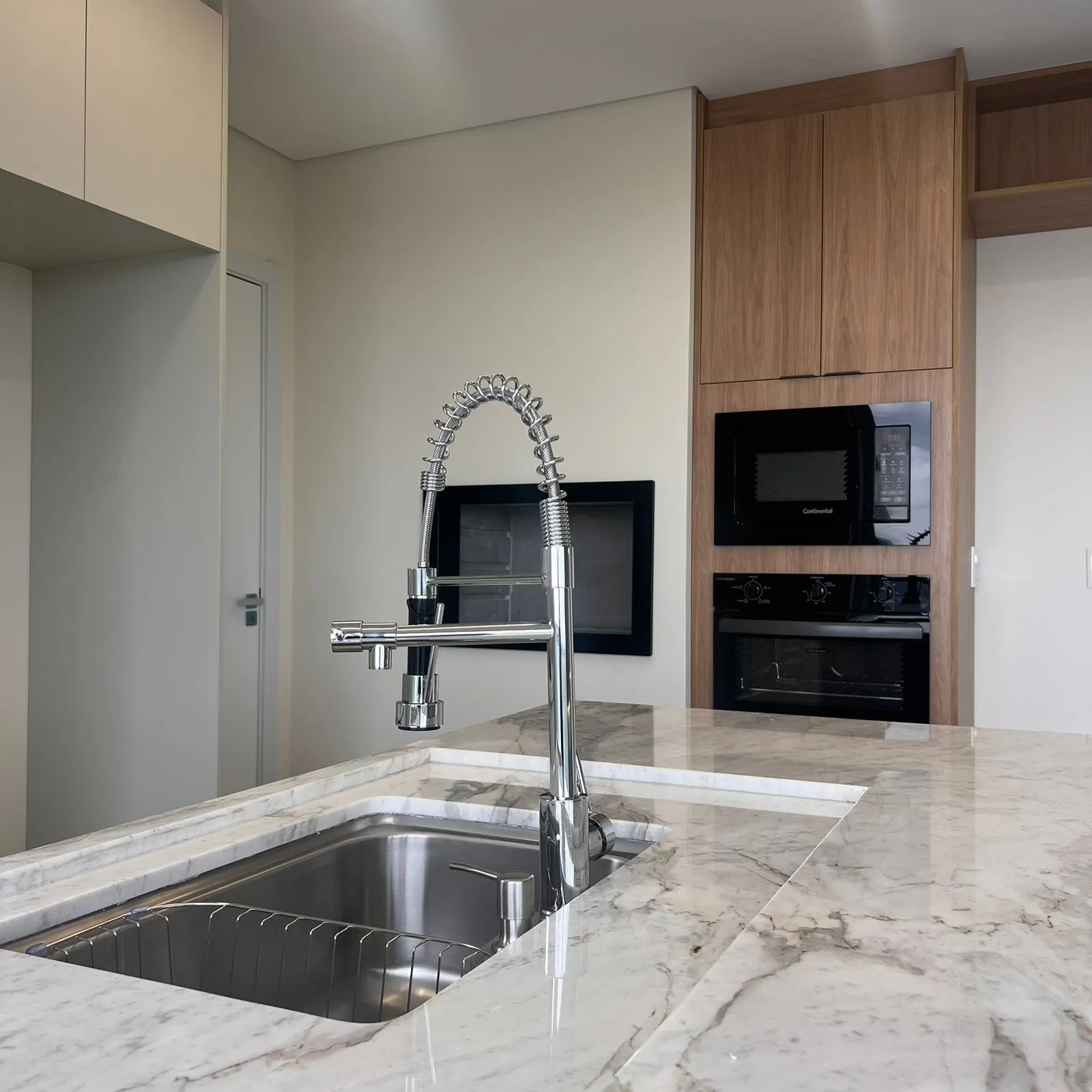 Detalhe de cuba e torneira sobre bancada de mármore em cozinha DOMOV