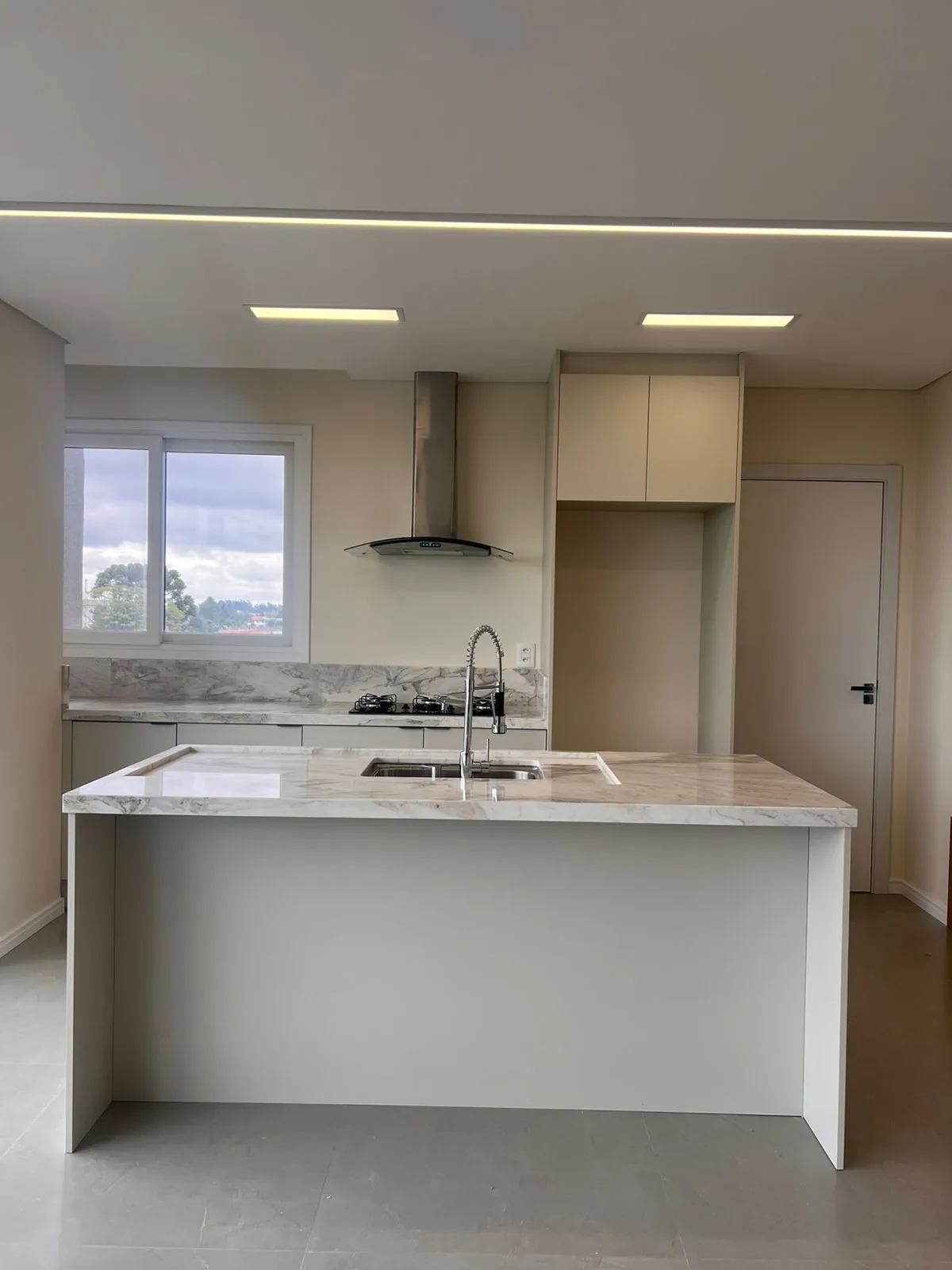 Ilha central com cooktop e coifa em cozinha planejada DOMOV