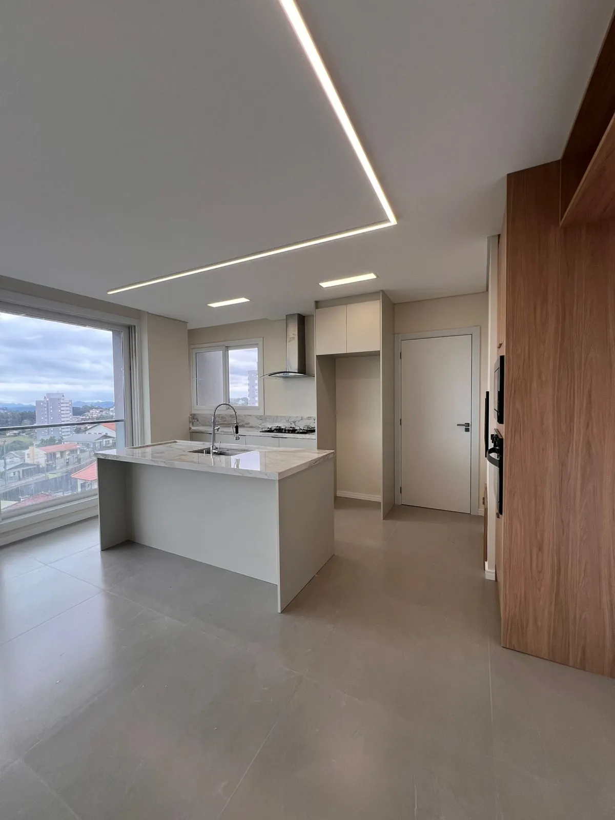 Ambiente integrado com marcenaria amadeirada e iluminação linear em projeto DOMOV